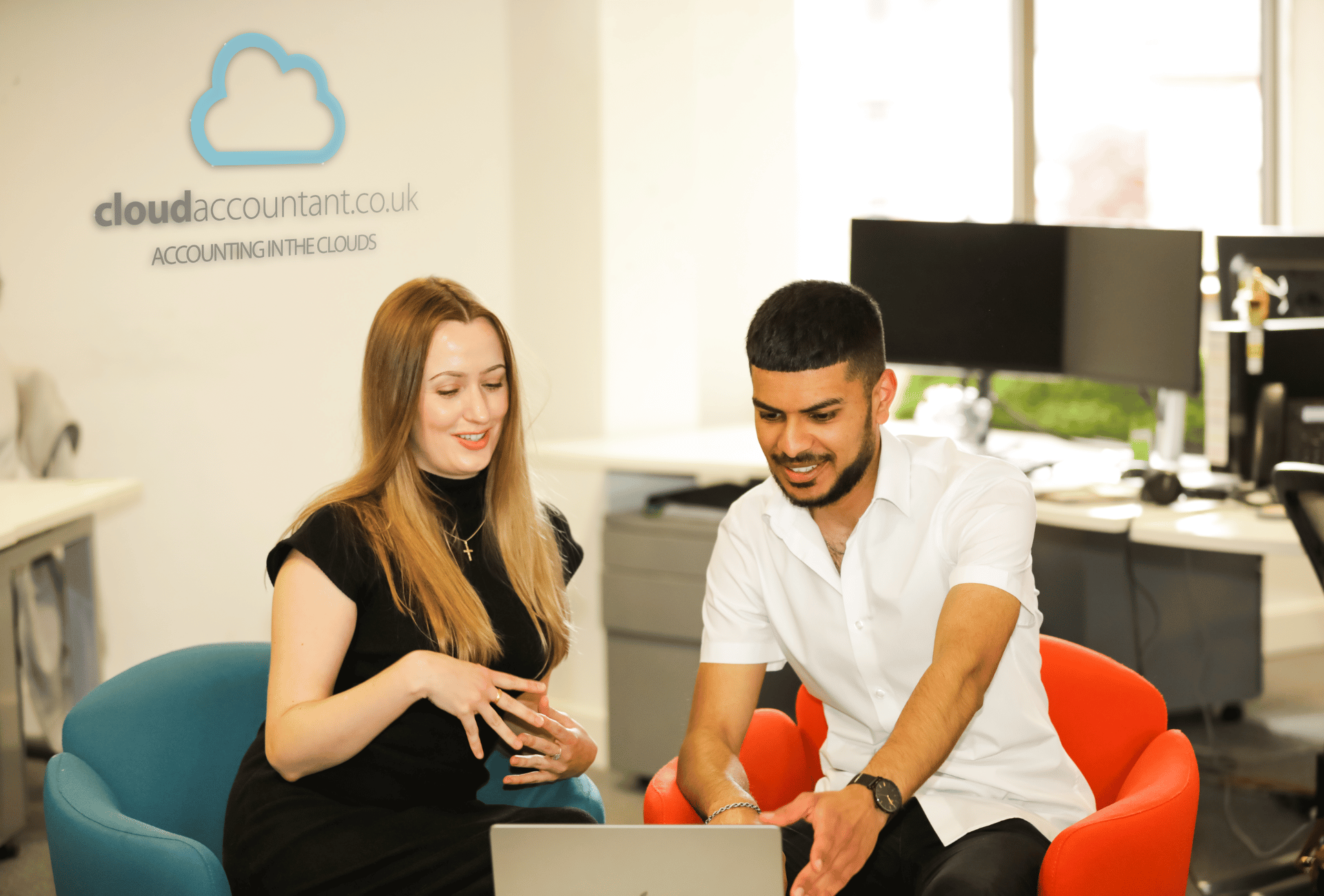 Accountants Rebecca and Sheraz hold a meeting together in the CloudAccountant.co.uk offices. They are looking at something on a laptop.